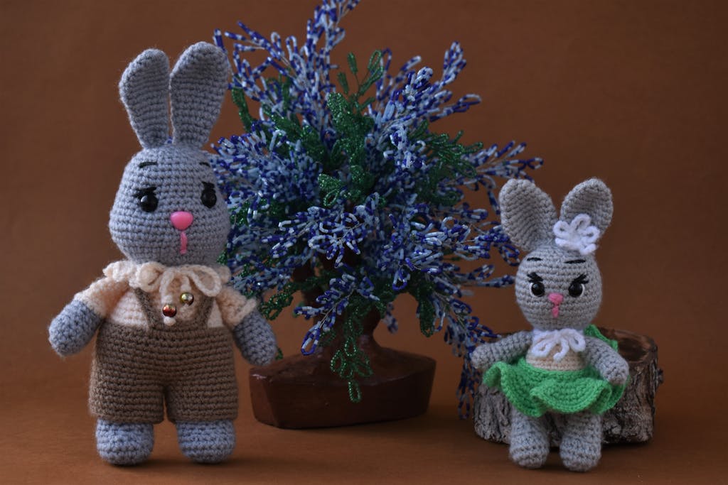 Charming handmade crochet bunny toys with decorative floral arrangement, perfect for gifting or decor.